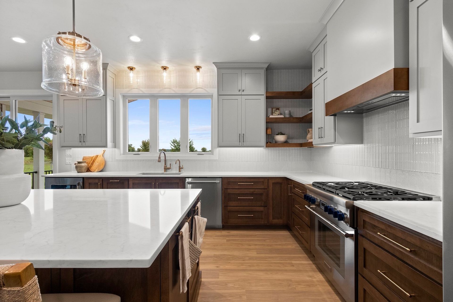 Modern kitchen with white quartz countertops, wooden cabinets, and stainless steel appliances.