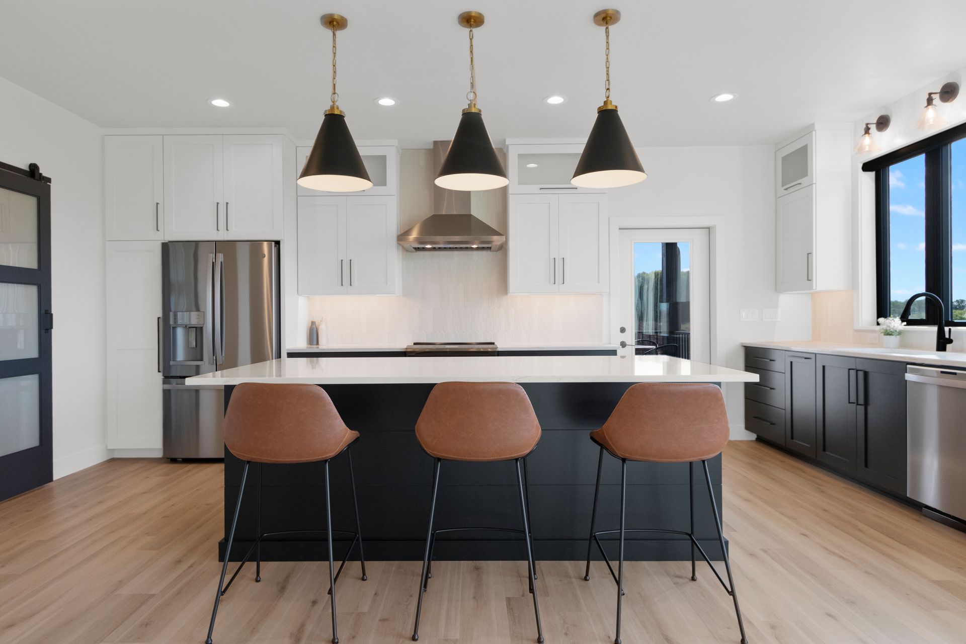 A kitchen with a large island and three bar stools.
