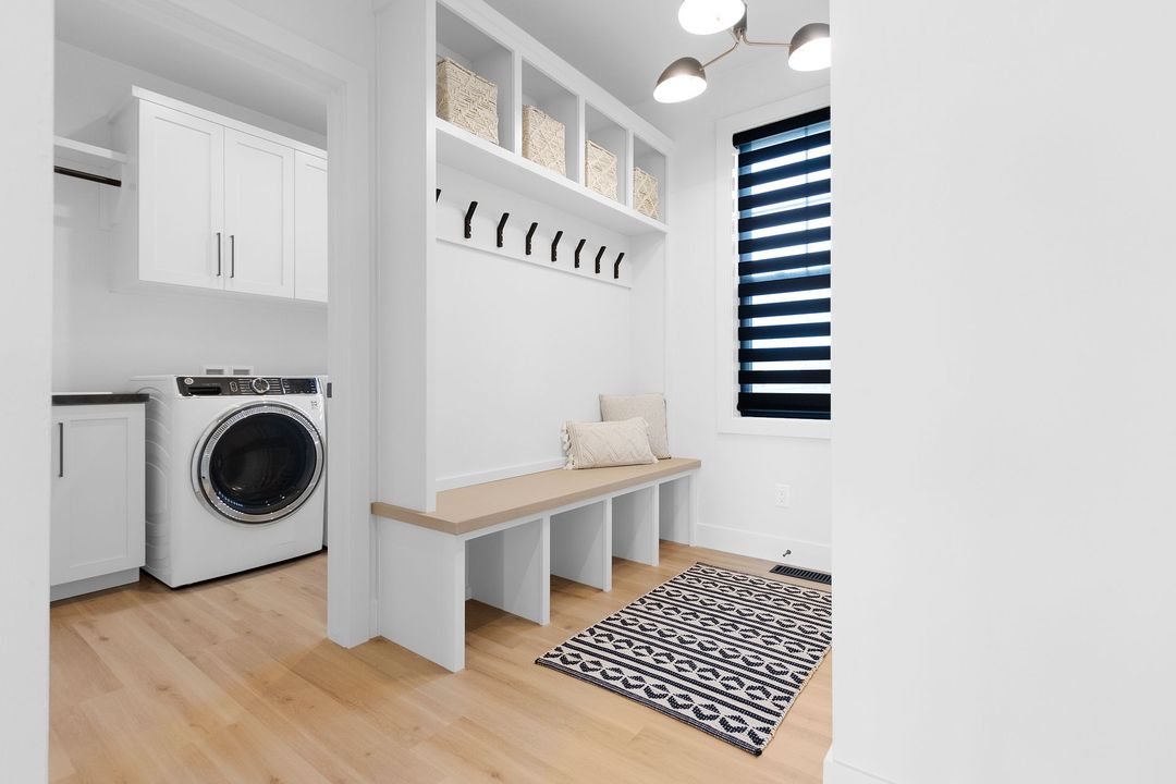 A laundry room with a washer and dryer and a bench.