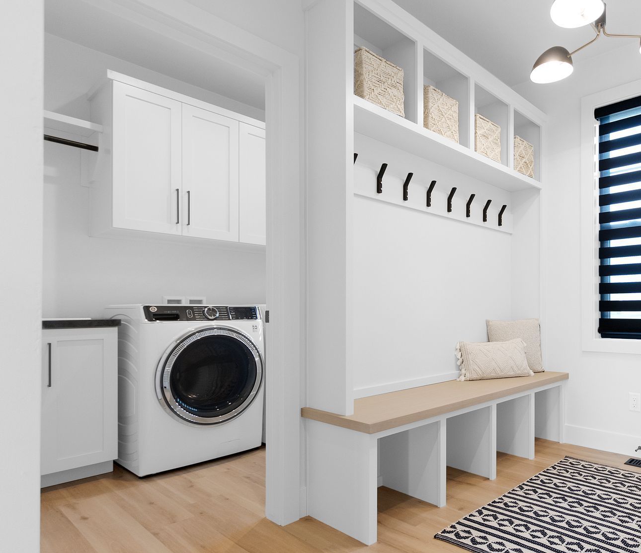 A laundry room with a washer and dryer and a bench.