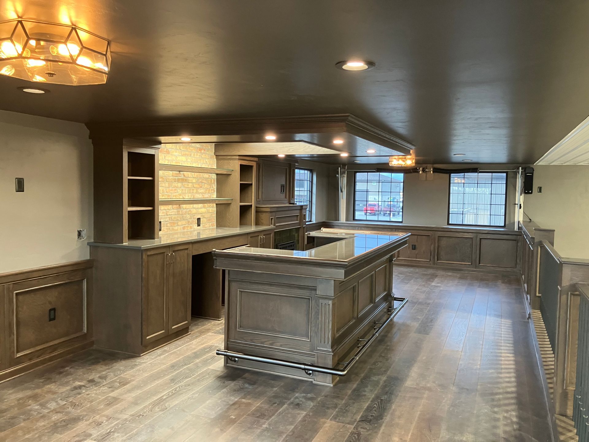 Finished home bar with cabinetry, countertops, and flooring in a wood-toned, dimly lit setting.