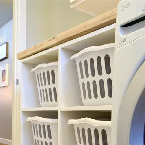 A laundry room with a washer and dryer and baskets