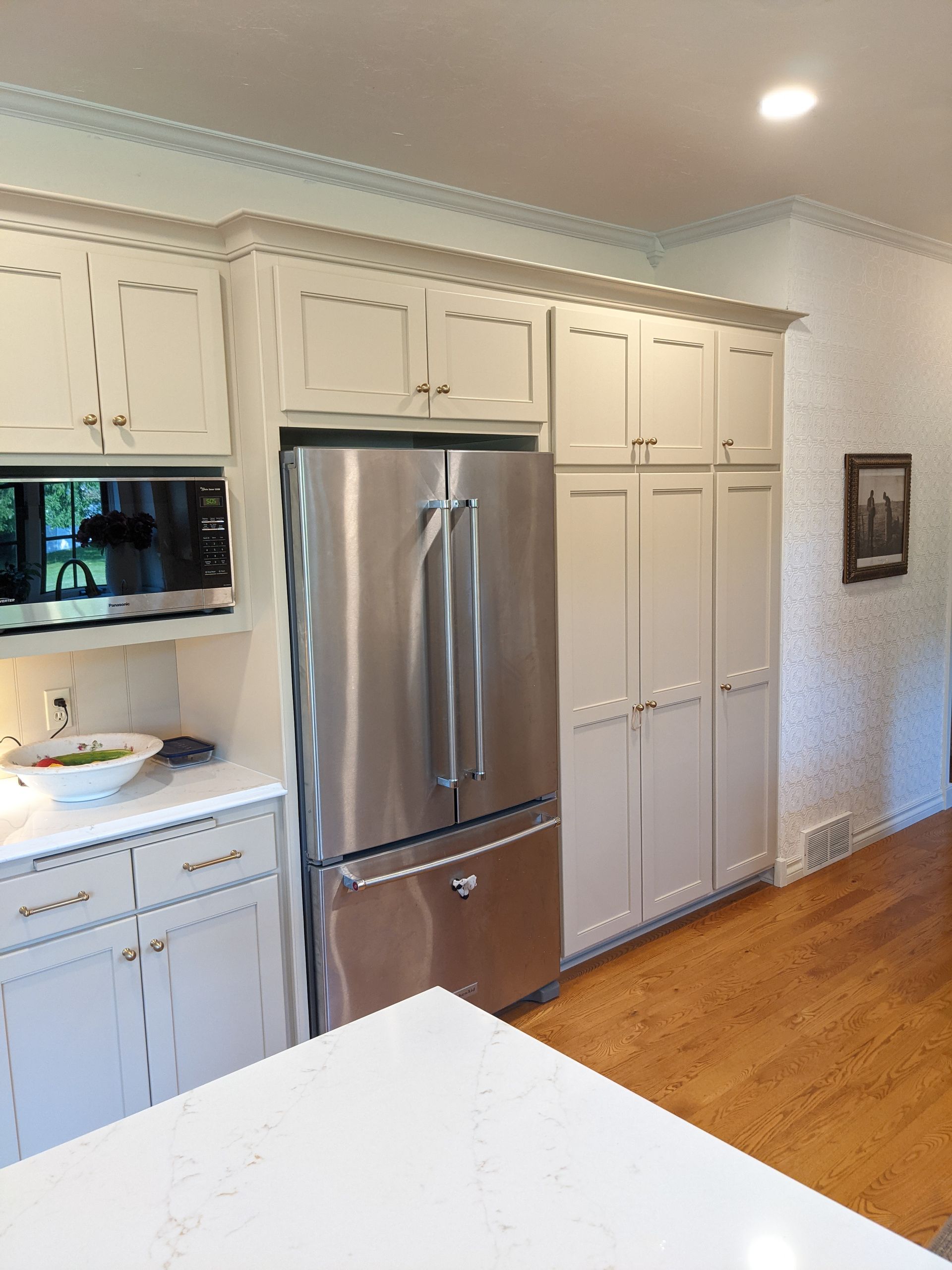 Kitchen with light cabinets, stainless steel fridge, and hardwood floors.
