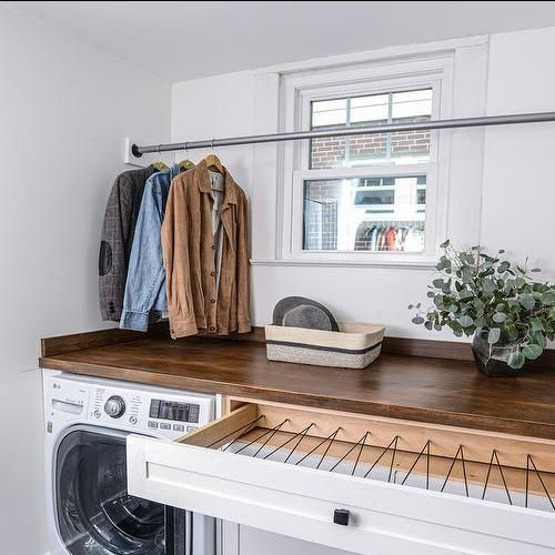 A laundry room with a washer and dryer and a wooden counter top.