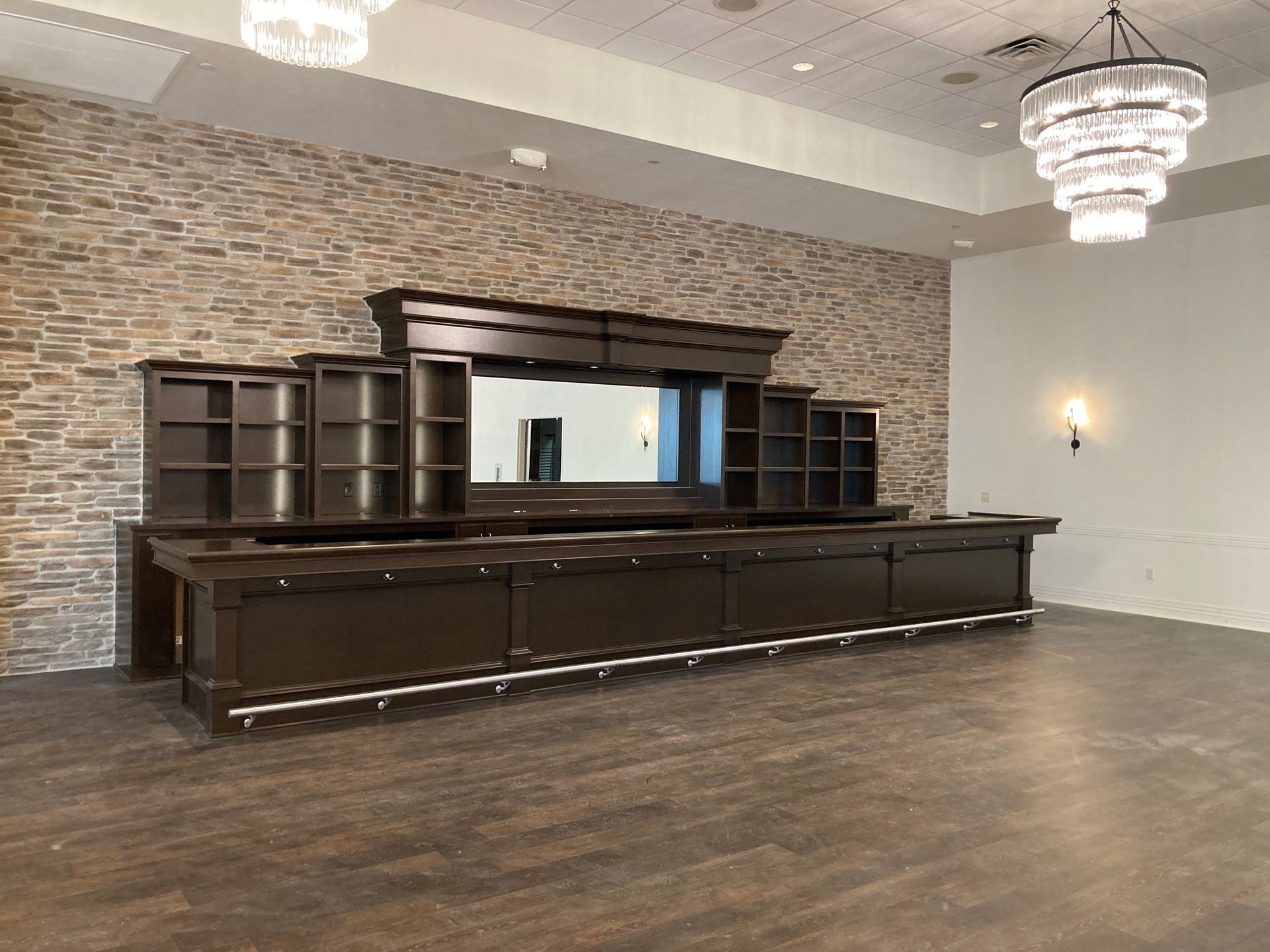 An empty room with a long wooden bar and a brick wall.