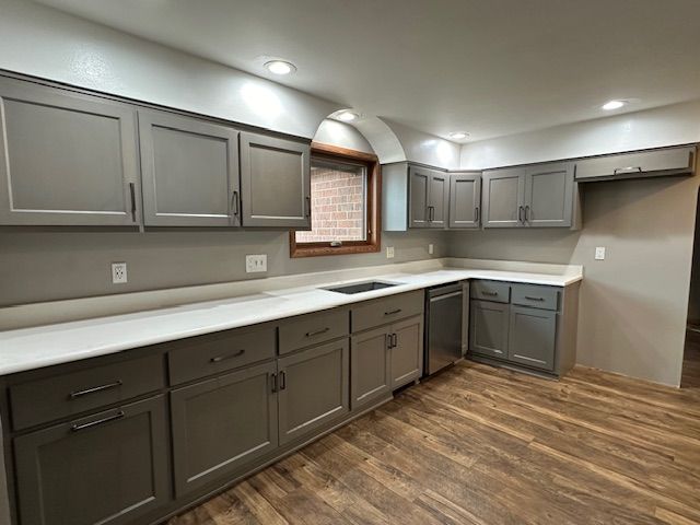 A kitchen with gray cabinets and white counter tops.