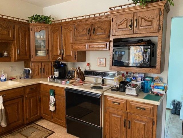 A kitchen with wooden cabinets , a stove , a microwave , and a sink.