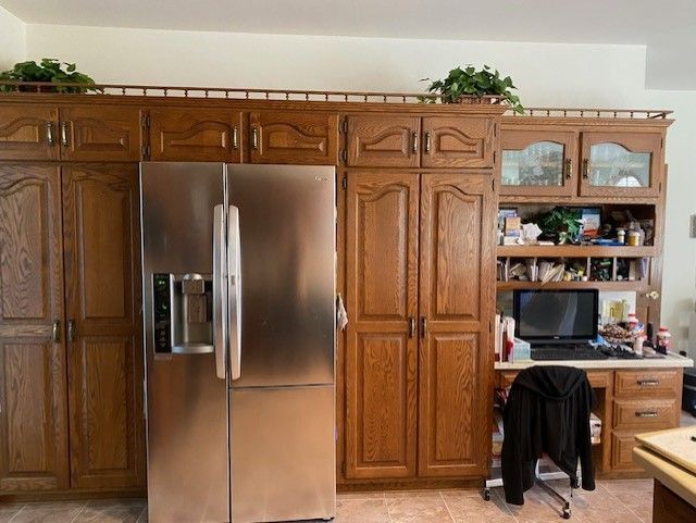 A kitchen with wooden cabinets and a stainless steel refrigerator