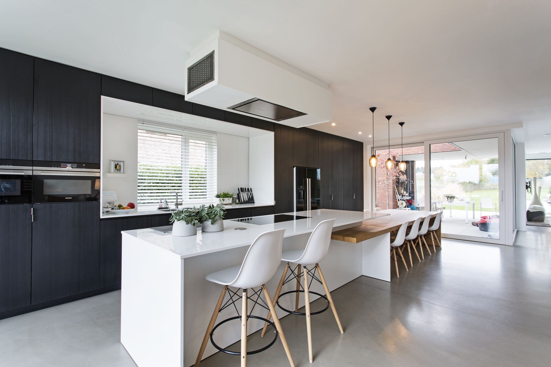 A kitchen with black cabinets and white counter tops and chairs.