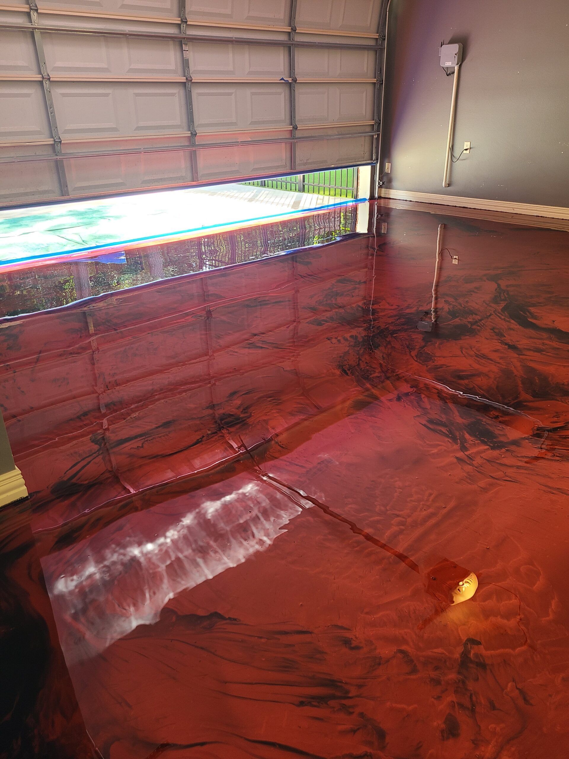A garage with a red epoxy floor and a garage door.