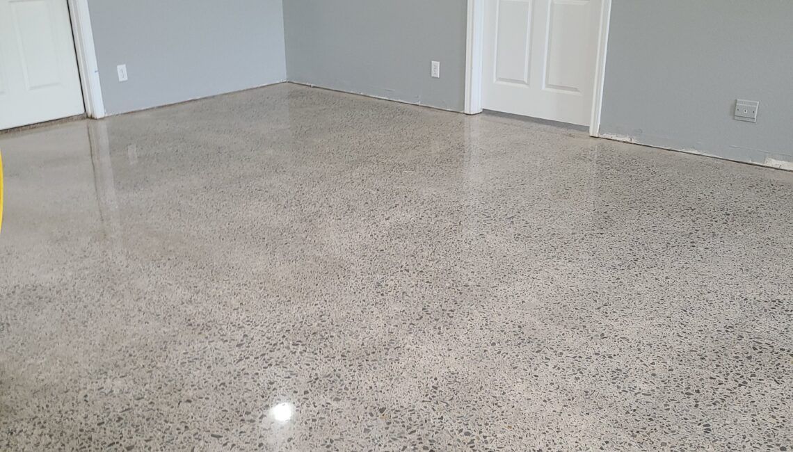 A room with a shiny concrete floor and gray walls.