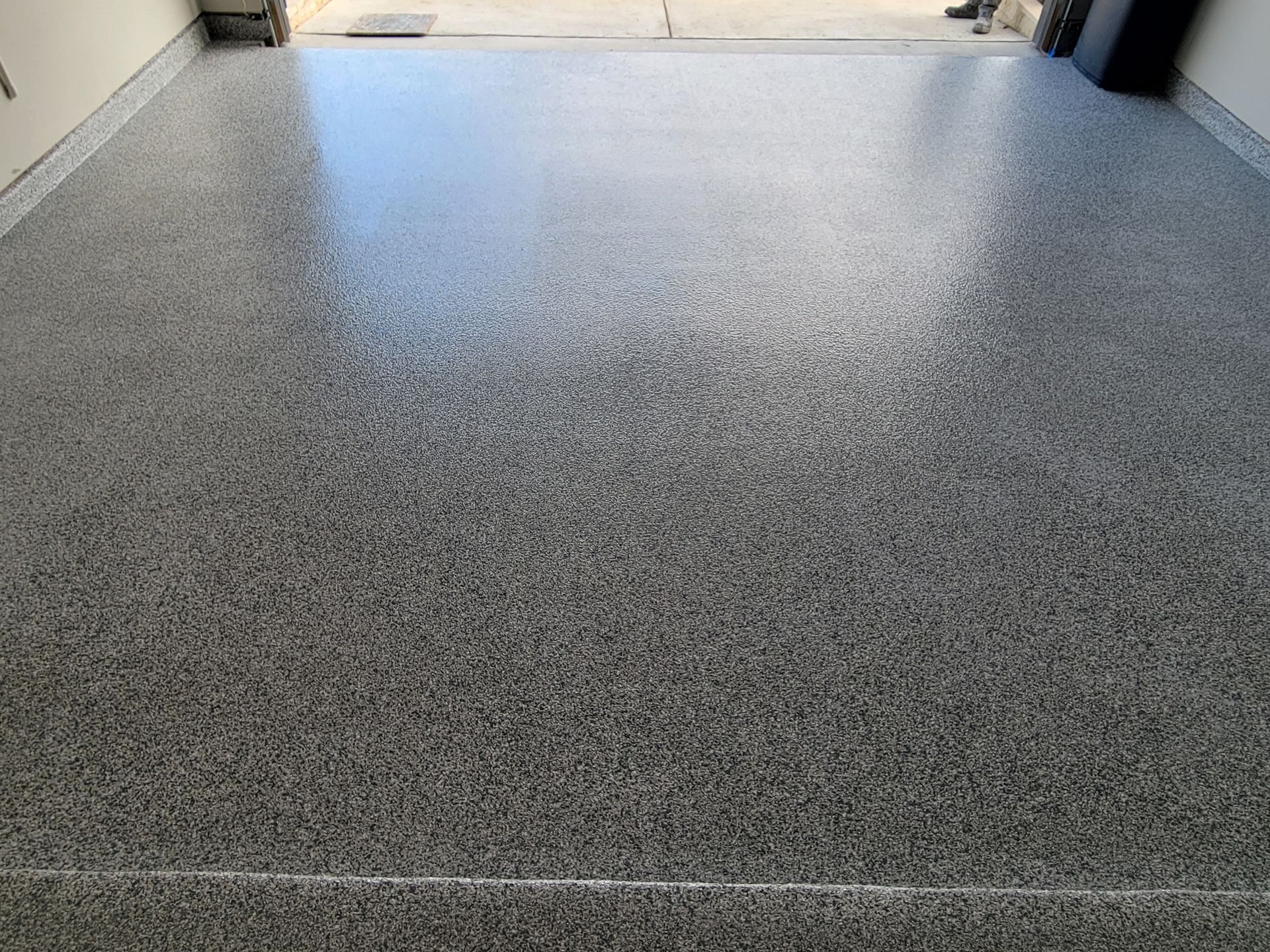 A close up of a gray concrete flaked floor in a garage.