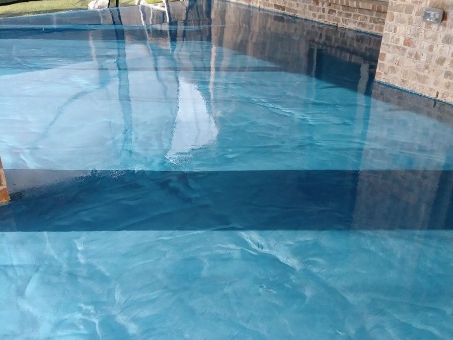 A blue swimming pool with a ladder in the background.