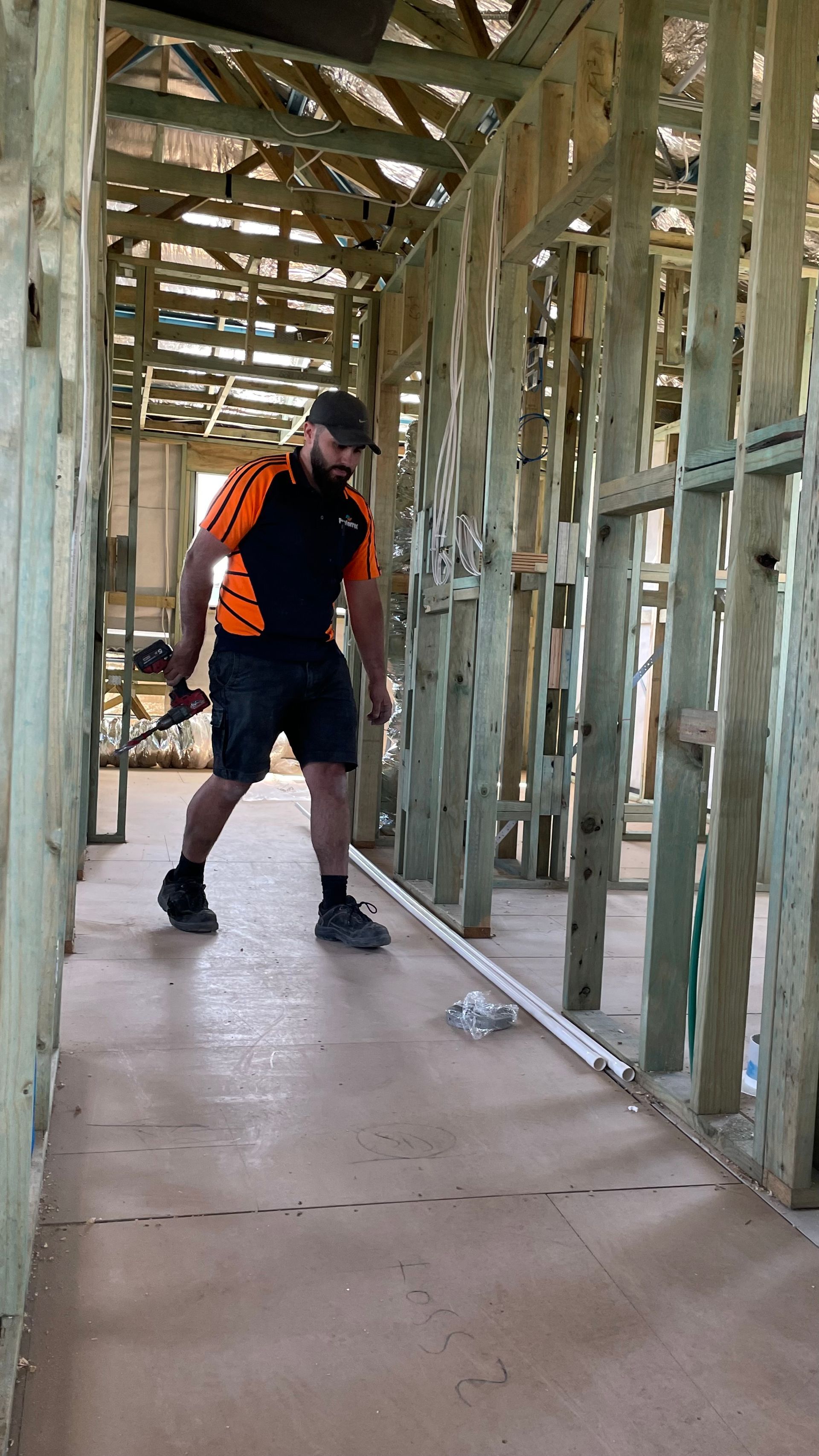 A man is measuring a piece of wood in a building under construction.