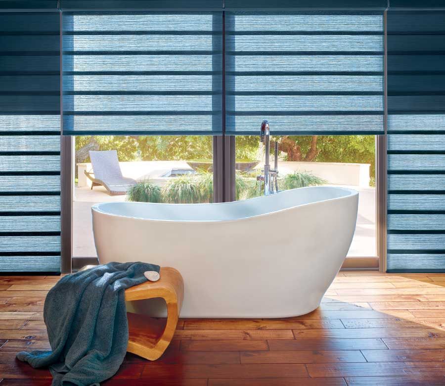 modern bathroom with white standing tub and dual shades on large windows