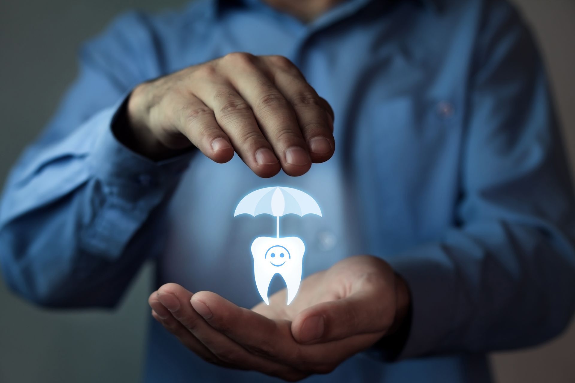 Man's hands cupped around a glowing tooth with a smiling face and a glowing umbrella above it.