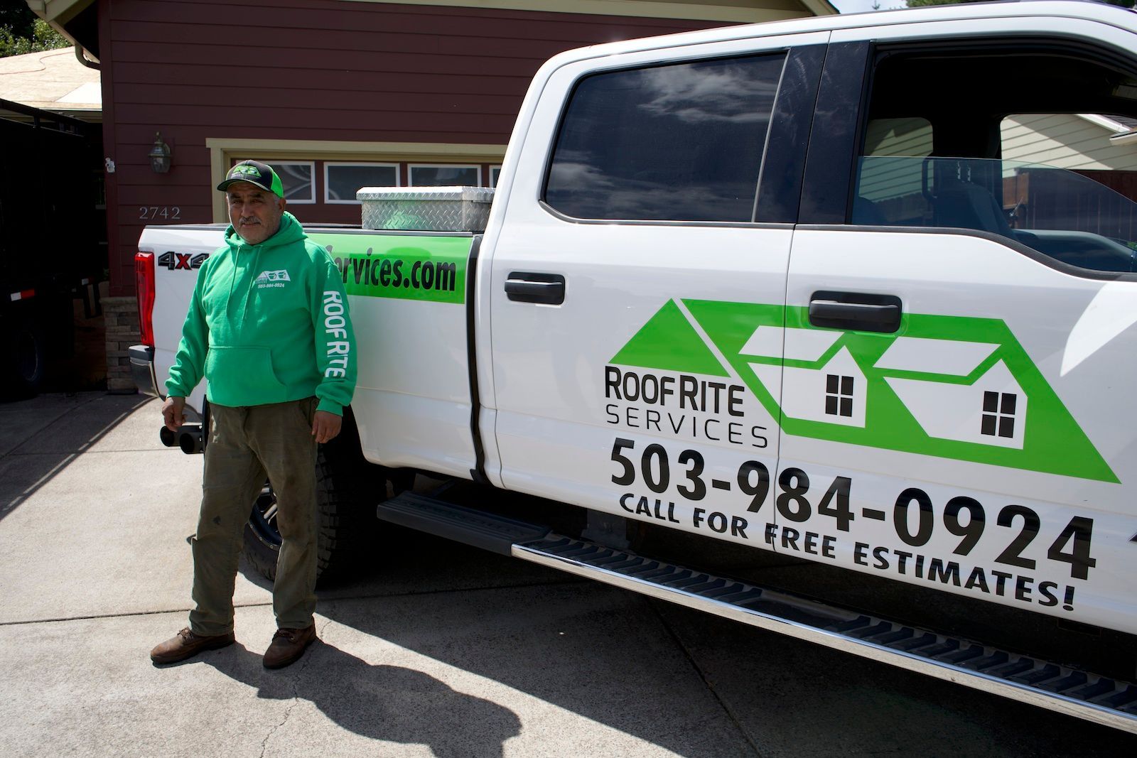 Man in green hoodie stands by a white truck with 