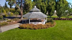 Gazebo in a park surrounded by greenery and a pathway.