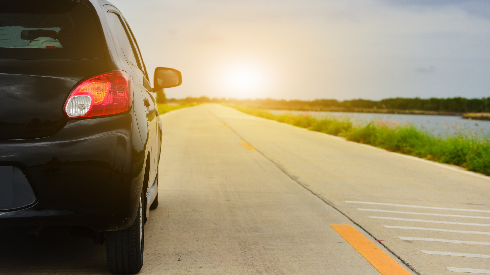A car is parked on the side of a road at sunset.