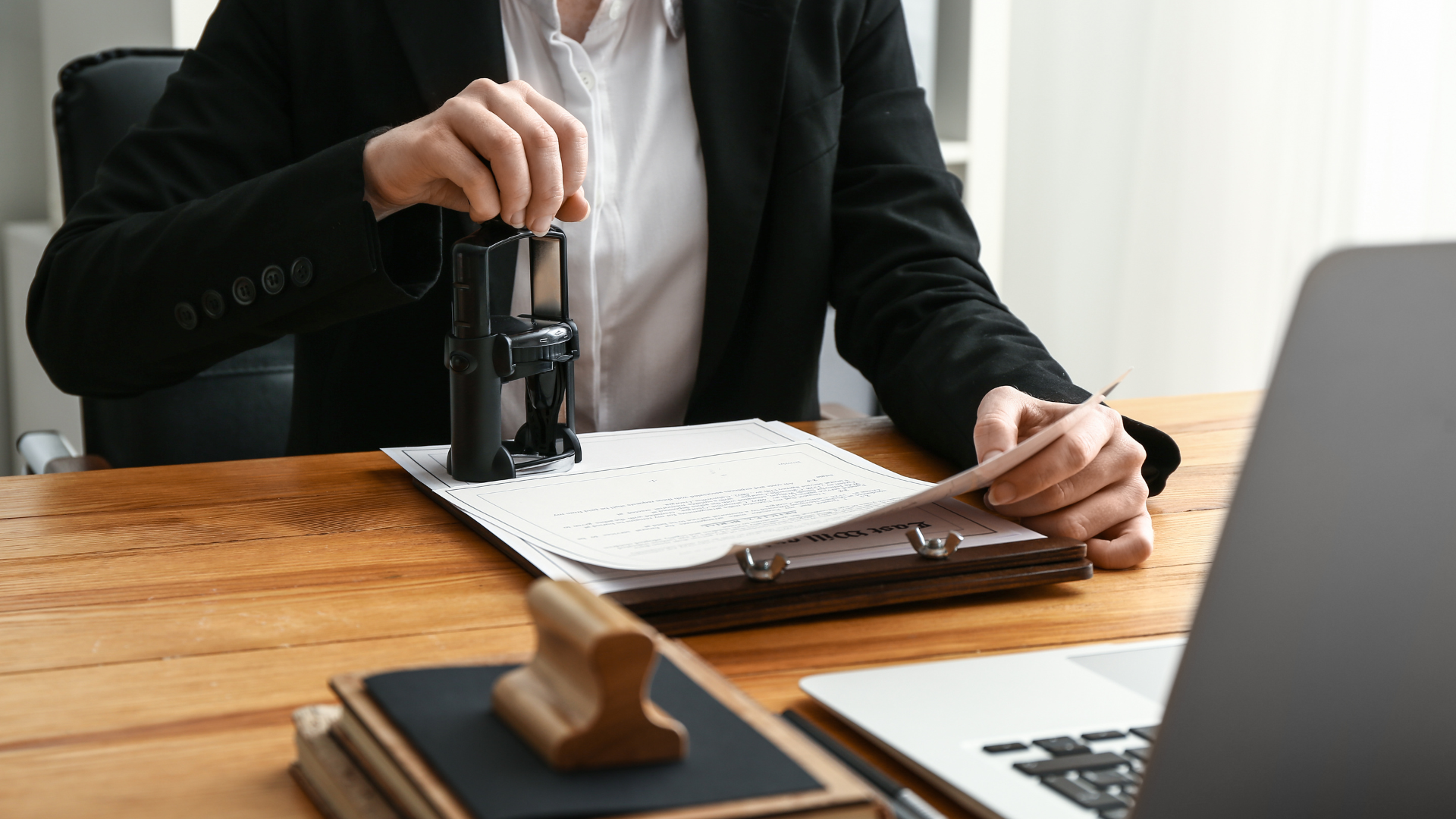 A man is sitting at a desk using a stamp on a piece of paper.