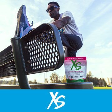 A man is sitting on a bench next to a bag of xs