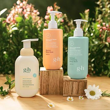 Three bottles of shampoo and conditioner are sitting on a wooden table.