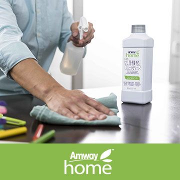 A person is cleaning a table with an amway home product