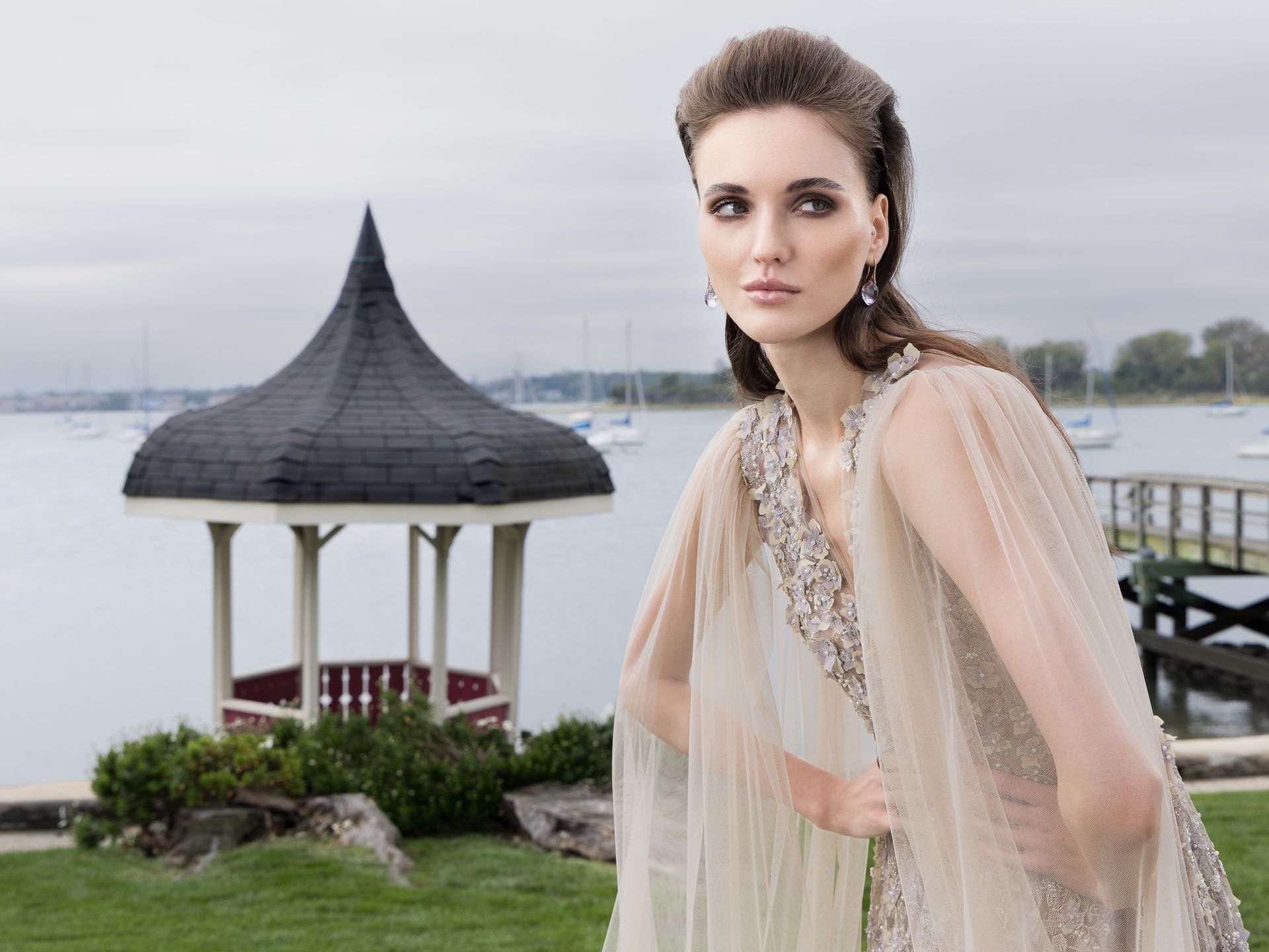 A woman in a white dress is standing in front of a gazebo