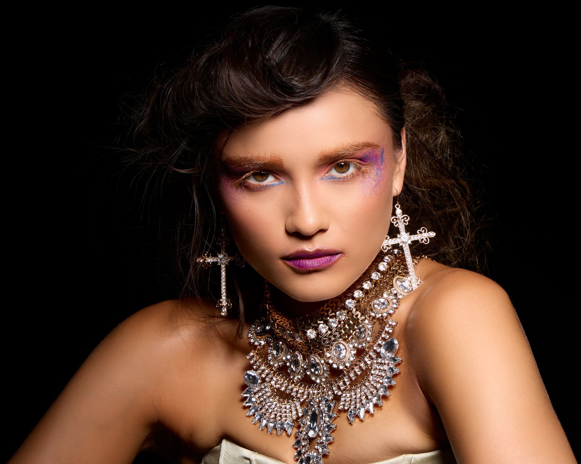 A woman wearing a necklace and earrings looks at the camera