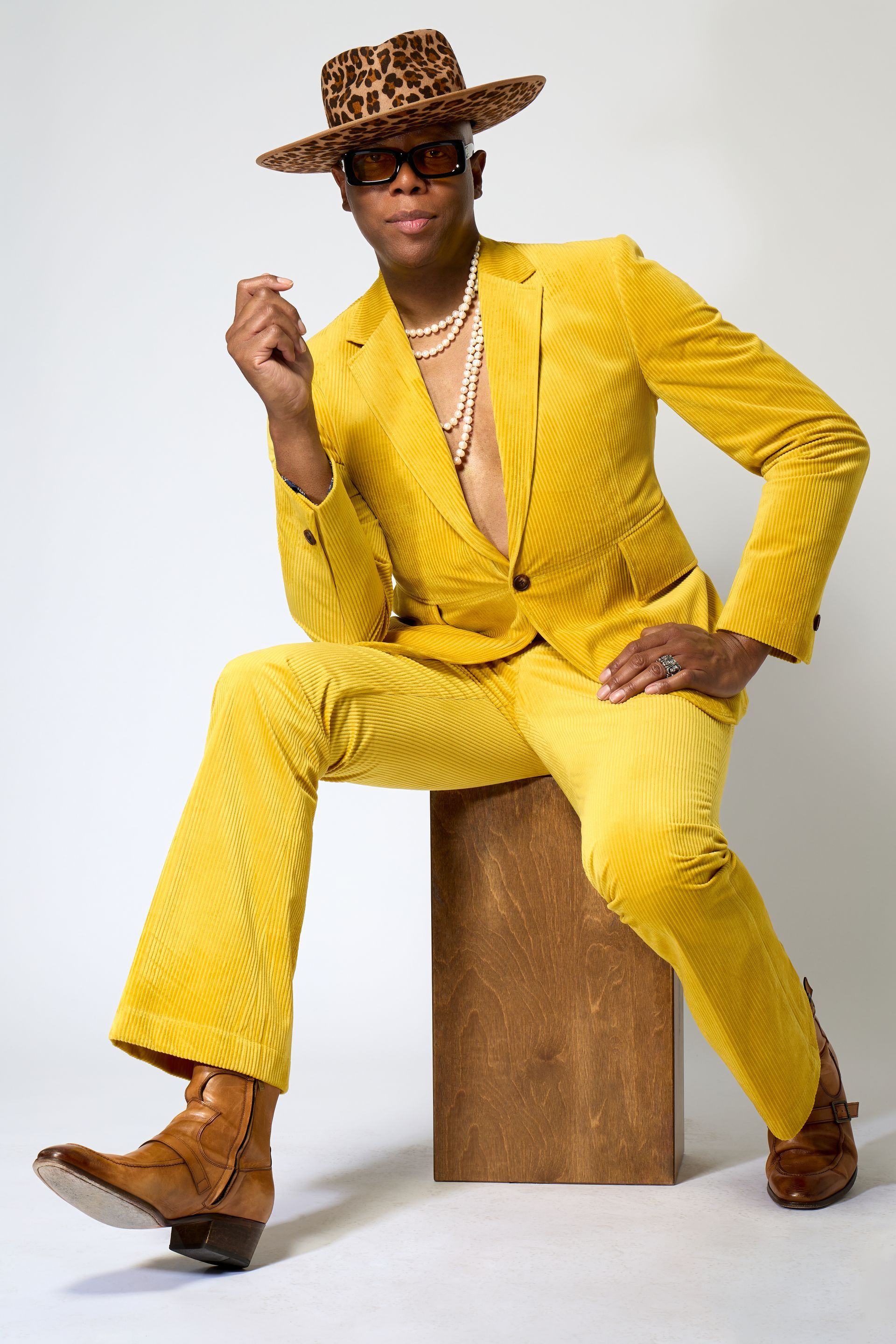 A man in a yellow suit and hat is sitting on a wooden box