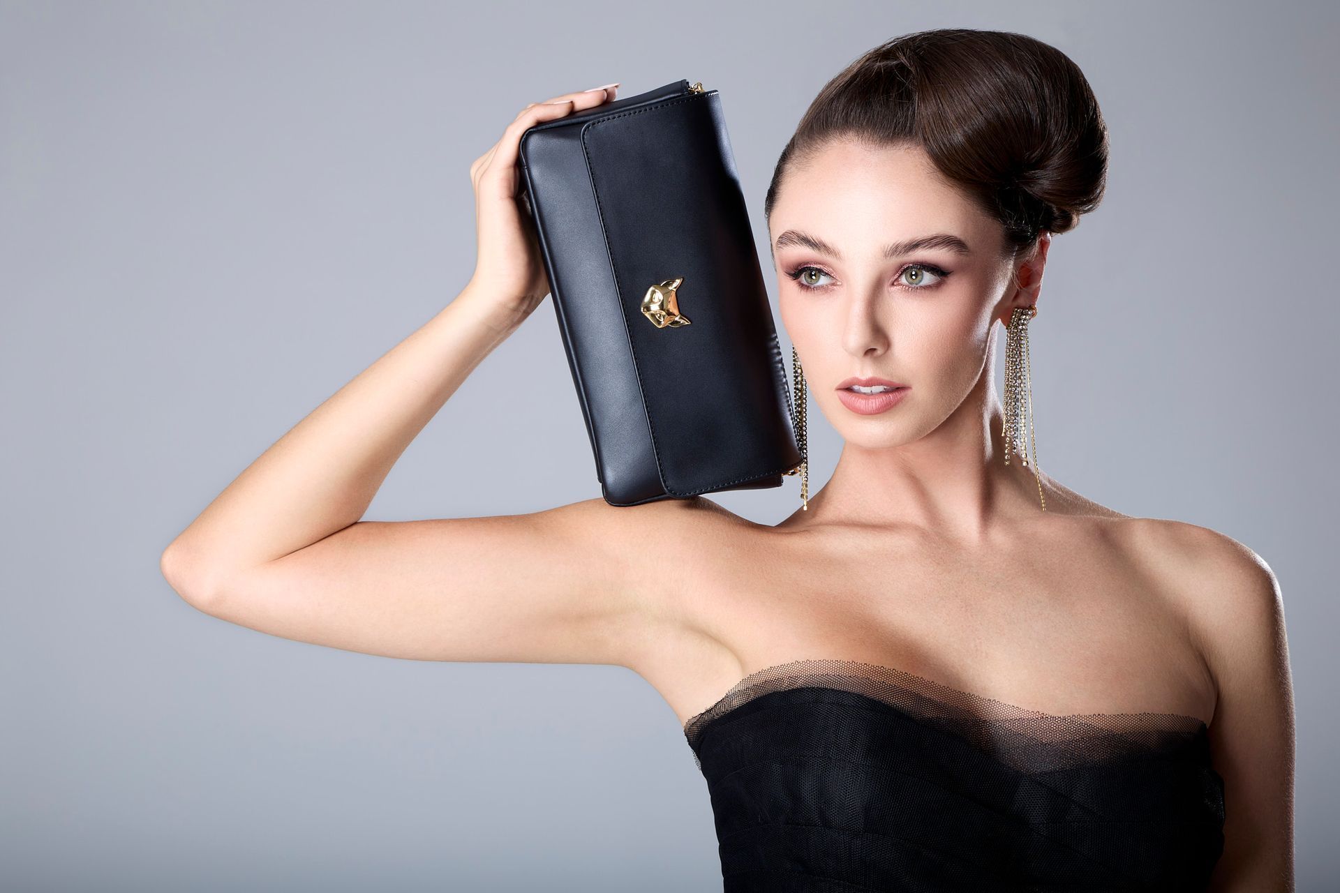 International top model wearing a black strapless dress and earrings, with purse for NY Fashion week.