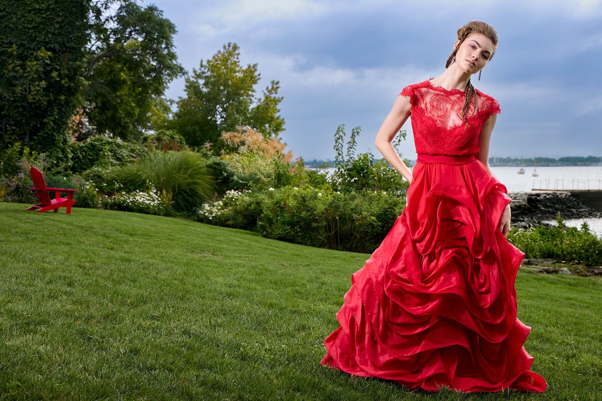 International vogue model in high-end evening gown. Standing in the grass near a body of water.