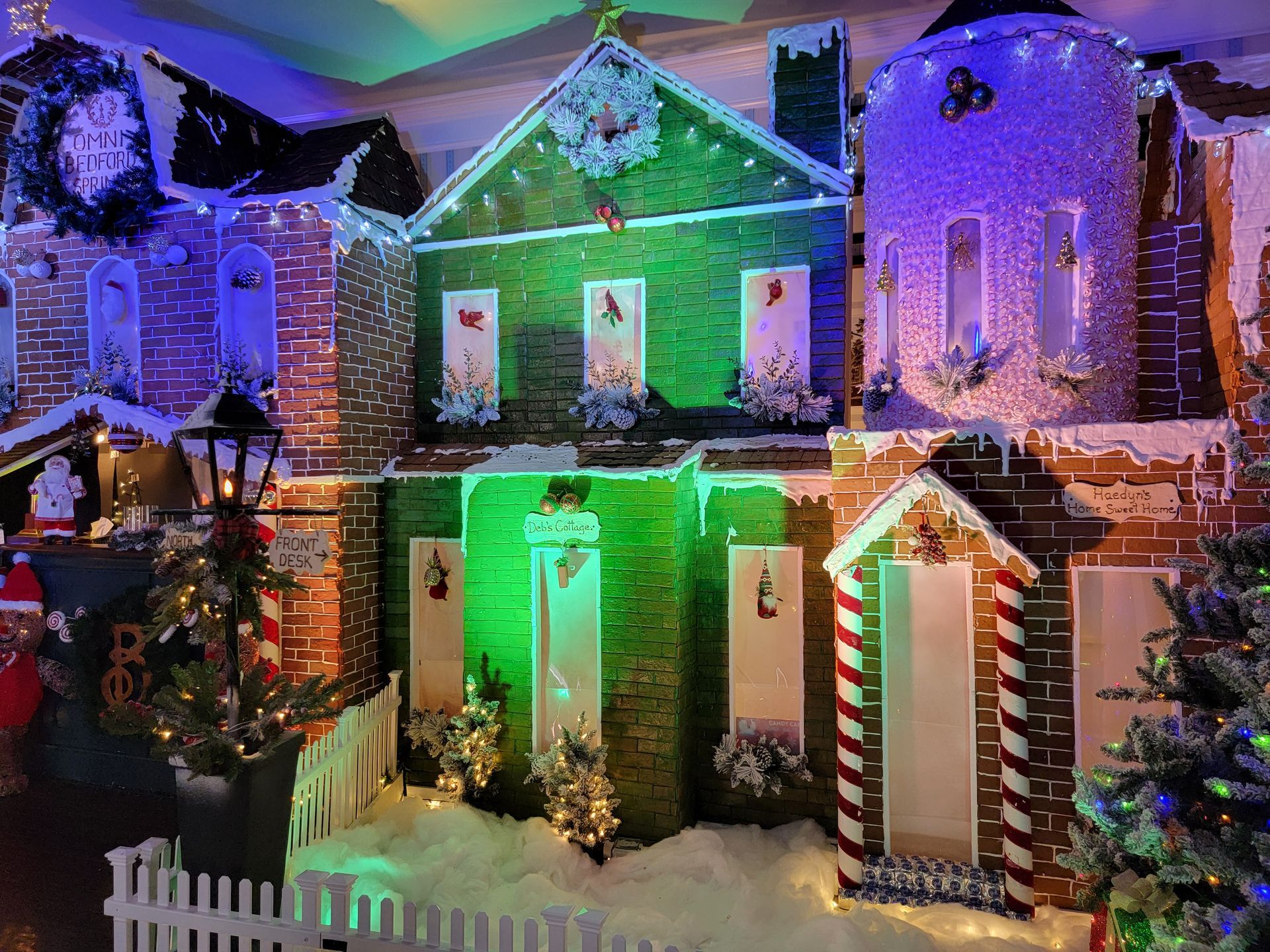 A dimly lit event space featuring a long bar, tables with red tablecloths, seating areas, and hanging globe lighting.