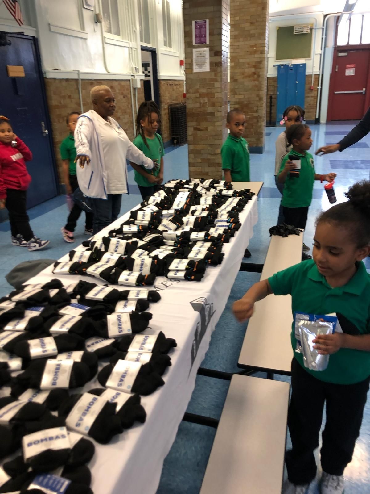 A group of children are standing around a table full of socks.