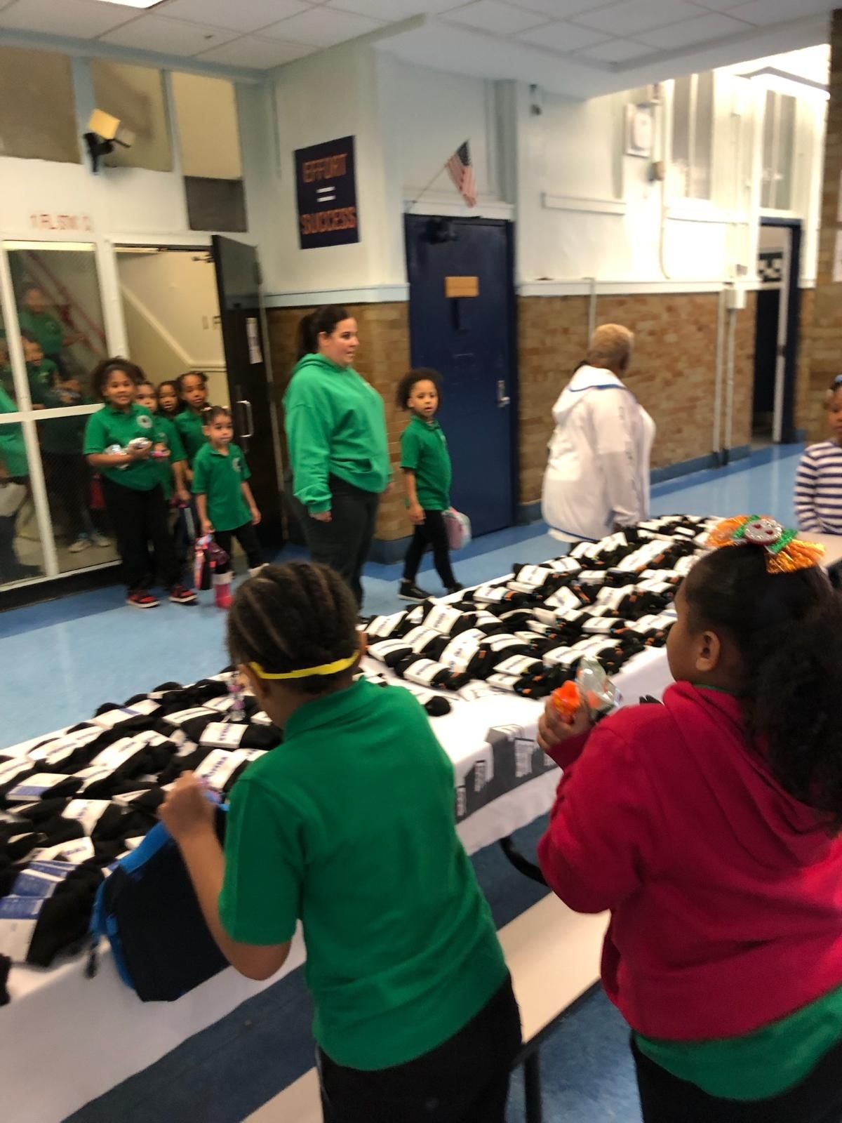 A group of children are standing around a table in a hallway