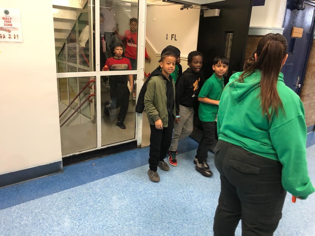 A group of children are standing in a hallway.