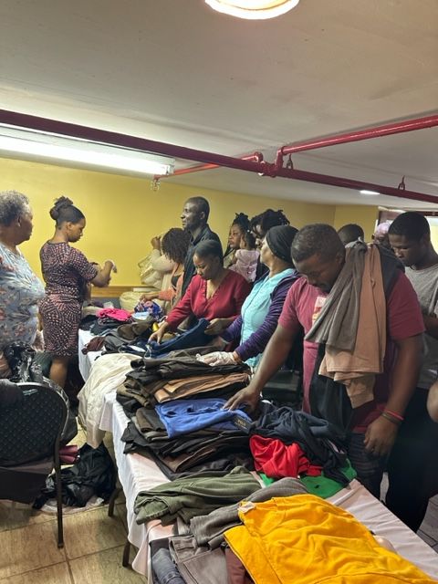 A group of people are standing around a table full of clothes.