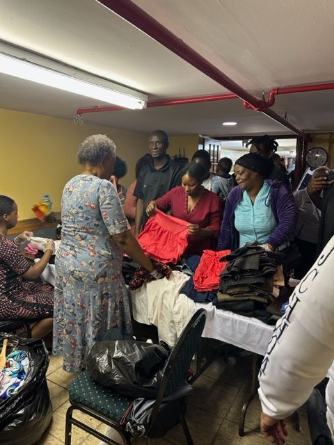 A group of people are gathered in a room looking at clothes.