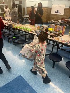 A little girl is standing in front of a table full of toys.