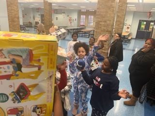 A group of children are standing around a box in a room.