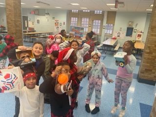 A group of children in pajamas are posing for a picture in a school cafeteria.
