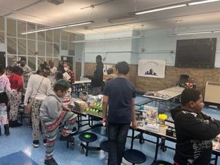 A group of children are standing around tables in a school cafeteria.