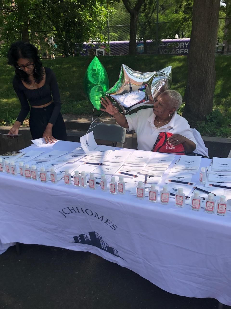 A woman is standing next to a man sitting at a table.