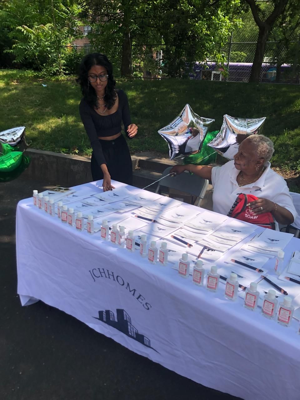 A woman is standing next to an older woman at a table with balloons.