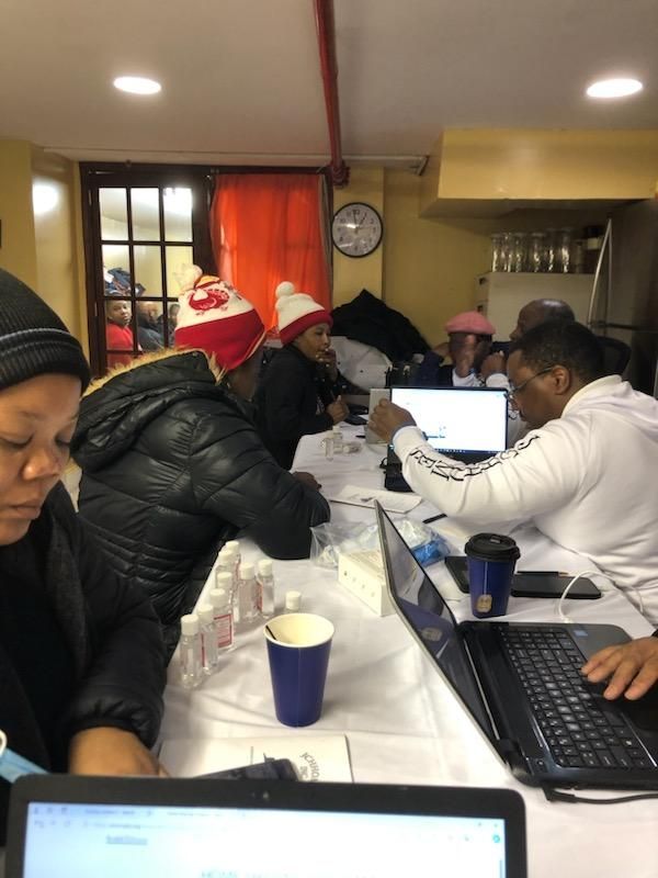 A group of people are sitting at a table with laptops