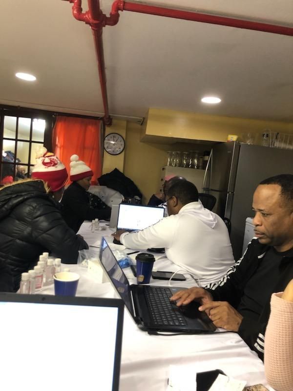 A group of people are sitting at a table with laptops
