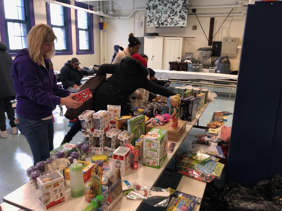 A group of people are standing around a table filled with food and toys.