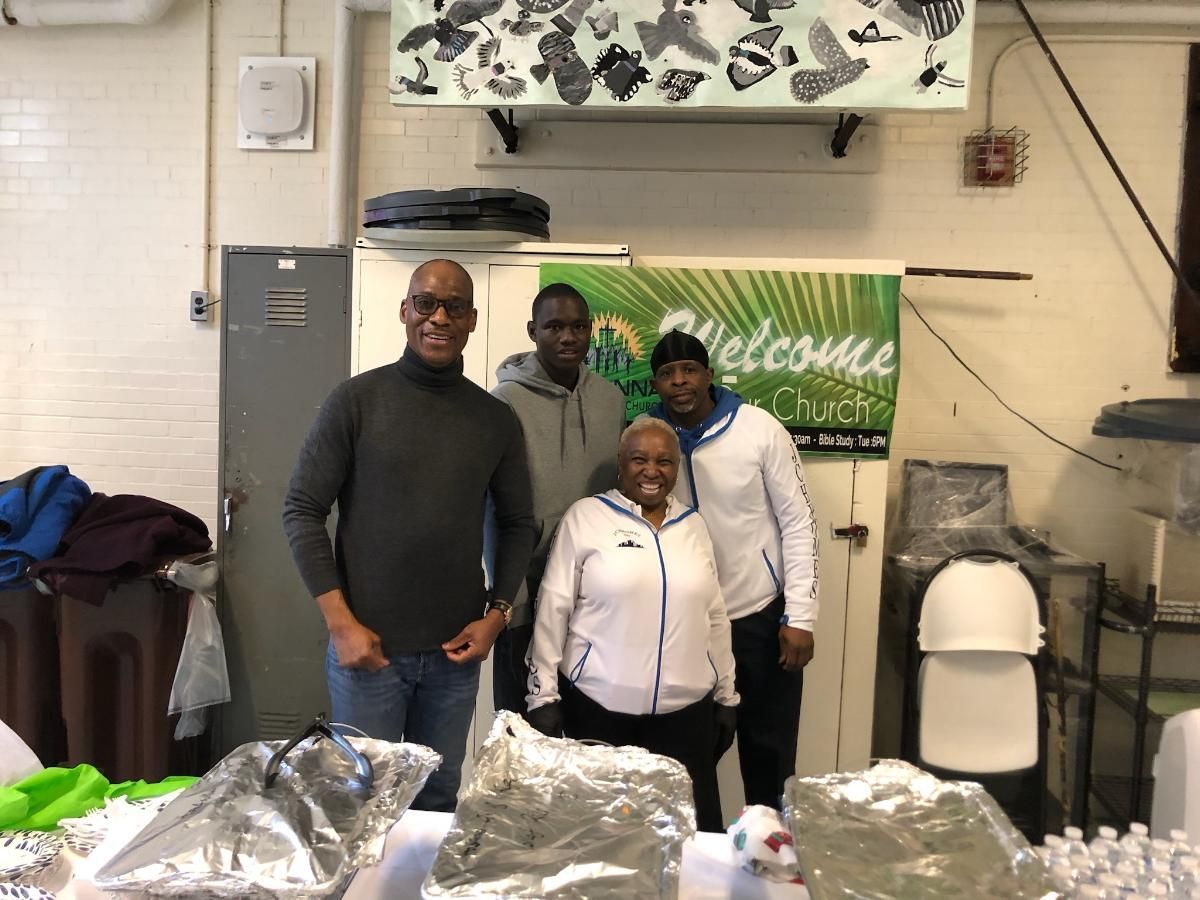 A group of people are standing in front of a welcome sign.