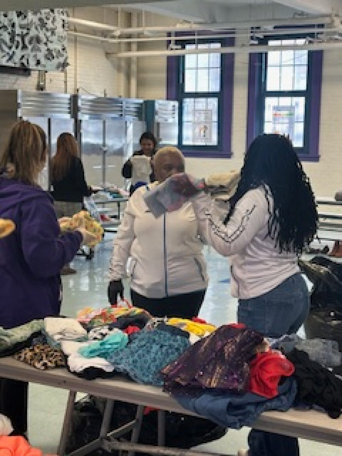 A group of women are standing around a table filled with clothes.