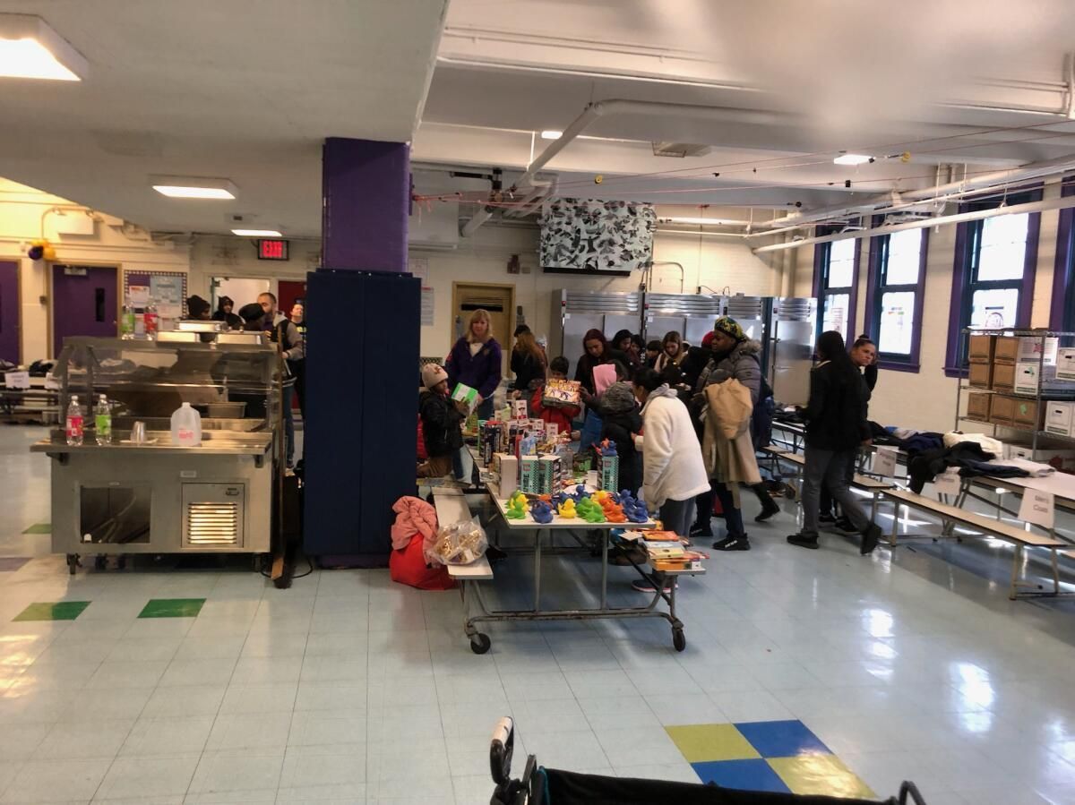 A group of people are standing around tables in a large room.